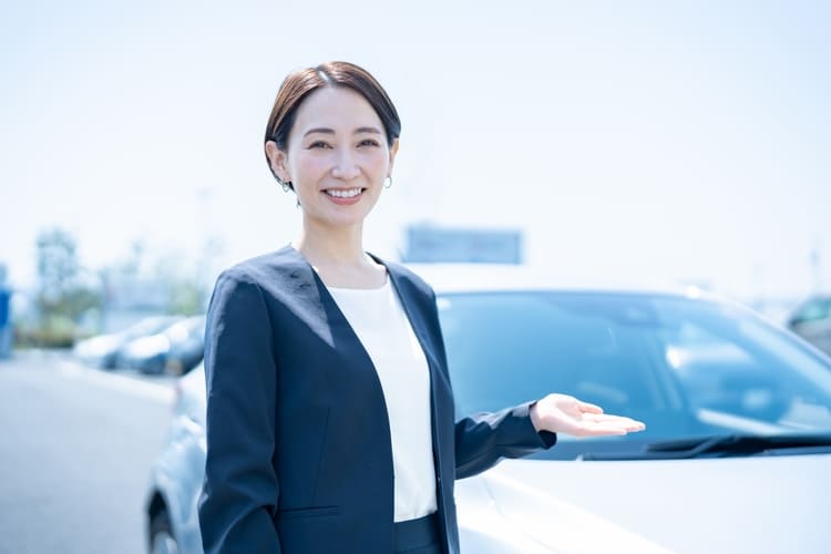 車の前で手を差し出す女性