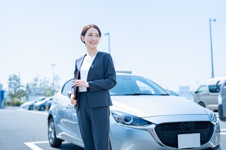 グレーの車の前に立つ女性