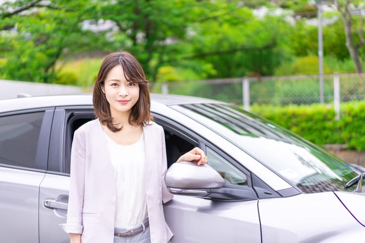 グレーの車の横に立つ女性スタッフ